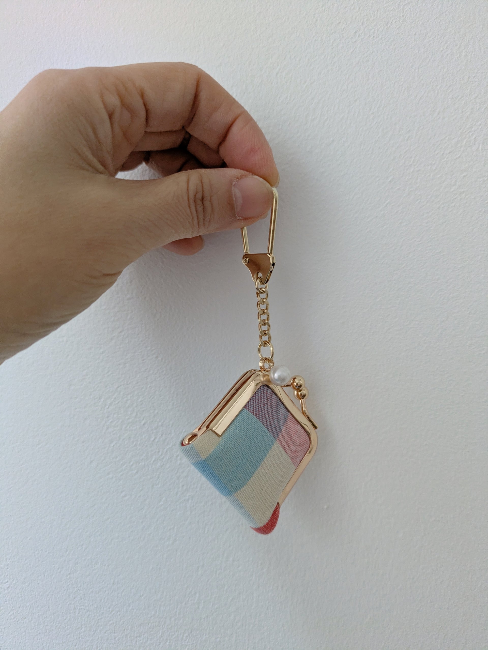 Colorful striped keychain held by a hand against a white background