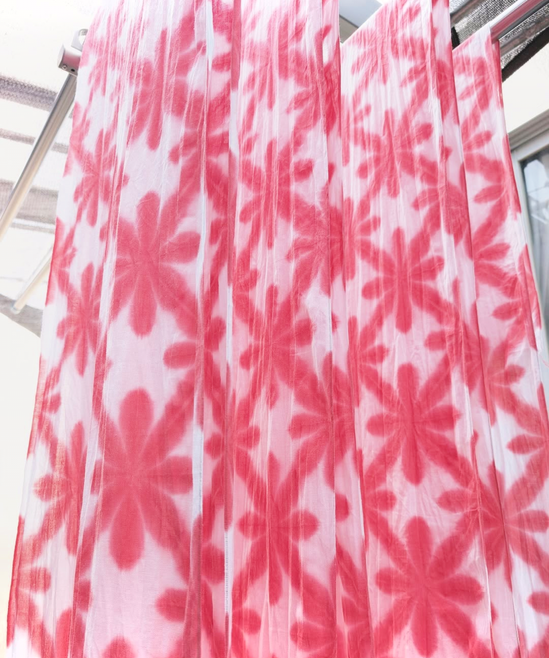 Pink floral patterned tenugui fabric hanging on a rack
