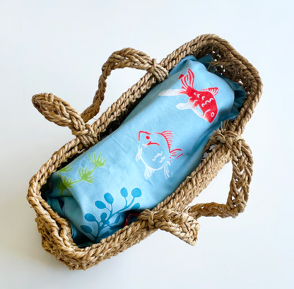 Woven basket with a tenugui featuring fish designs on a white background
