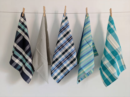 Set of five patterned towels hanging on a line against a white background