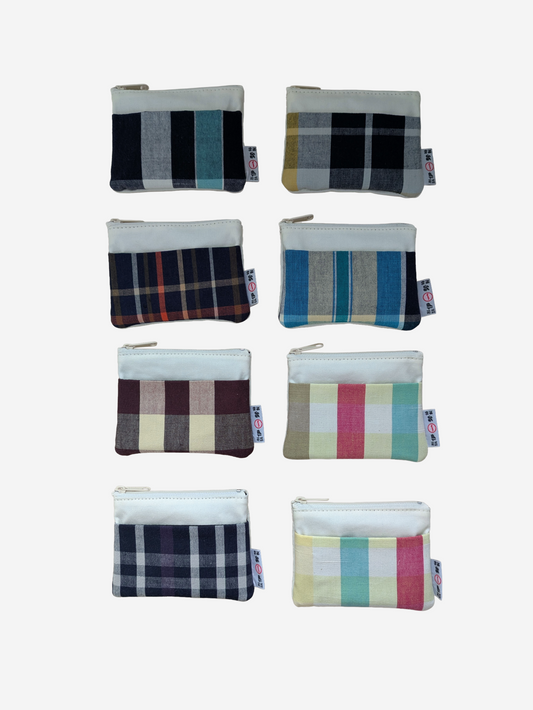Eight small zip pouches arranged in a 2-by-4 grid on a plain white background. Each pouch has a different plaid or stripe pattern in muted colours, including navy, grey, teal, burgundy, pink, green, and cream.