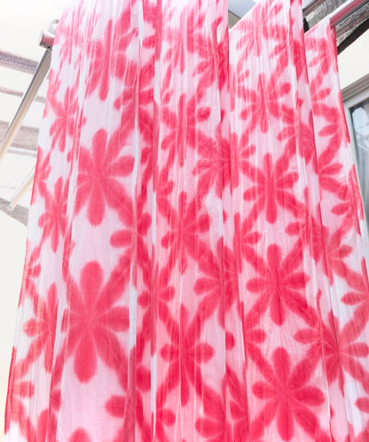 Pink floral patterned tenugui fabric hanging on a rack